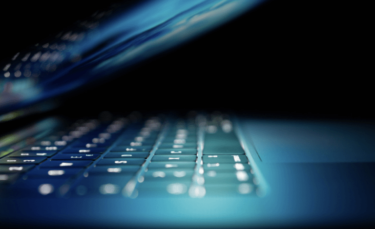 A close up of a MacBook keyboard illuminated